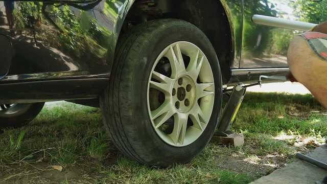 lifting the car with a jack screw to replace the wheel