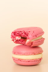 Two pink macaroons in a stack, one of them bitten off.