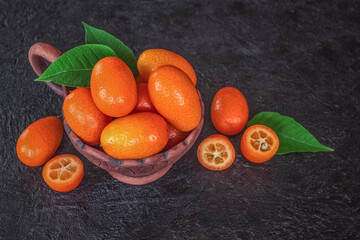fresh ripe kumquat in a ceramic bowl close-up. kumquat on a wooden background. ripe kumquat close-up.