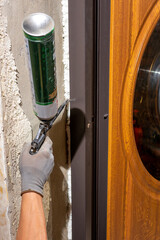 The worker foams and insulates the door, uses a carpenter's foam gun, a close-up of the work...