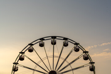 view of a ferris wheel in silhouette at sunset