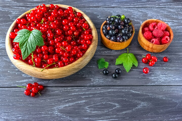fresh ripe currant and raspberry berries in wooden bowls. raspberry, red and black currant berries close-up. background with raspberries, red and black currants.