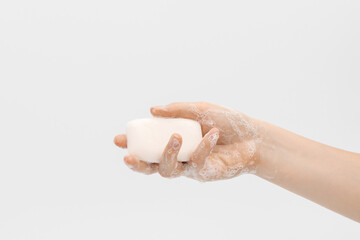 Bar of white soap in a woman's hand.