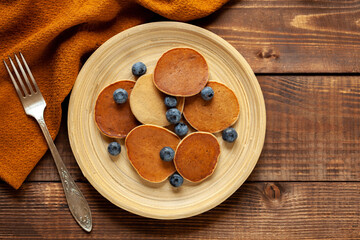 American pancakes with bananas and berries on wood background, top view