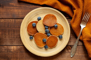 Pancakes with berries and bananas on dark wood table, top view