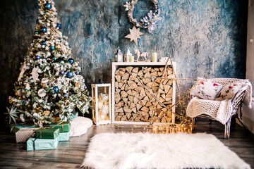 Living room decorated in New Year's style. The room has a Christmas tree with gifts, an armchair, a fireplace with wood and a white fluffy rug