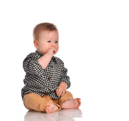 Baby boy in beige pants and a checkered shirt sitting on a white background.