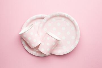 Polka dot disposable paper cups and plates on pink background