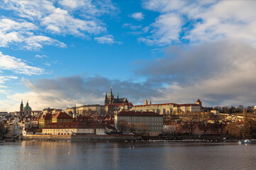 Obraz premium Beautiful view of Mala Strana old district of Prague on the Vltava river side with Wallenstein Palace, Prague Castle and St. Nicholas Church, on sunny winter day with blue sky cloud, Czech Republic