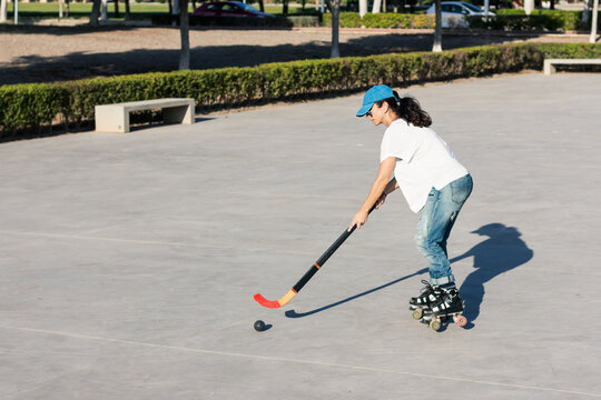 Girl Playing Roller Hockey In The Park.