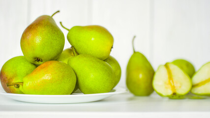 ripe pears in a white plate on a white background close-up. background with pears. green pears on a white background.