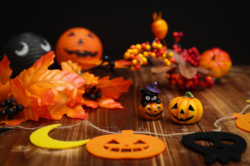 ハロウィンのイメージ素材　木目の上に置いた小さなカボチャと秋の葉や木の実の装飾　背景ボケ