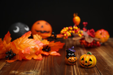 ハロウィンのイメージ素材　木目の上に置いた小さなカボチャと秋の葉や木の実の装飾　背景ボケ