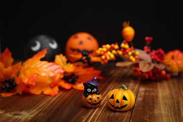 ハロウィンのイメージ素材　木目の上に置いた小さなカボチャと秋の葉や木の実の装飾　背景ボケ
