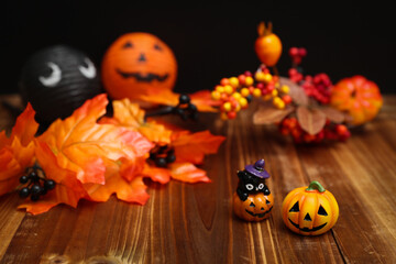 ハロウィンのイメージ素材　木目の上に置いた小さなカボチャと秋の葉や木の実の装飾　背景ボケ
