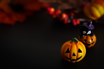 ハロウィンのイメージ素材　黒地にカボチャのクローズアップ　秋の葉と木の実などの背景ぼかし