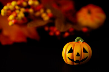 ハロウィンのイメージ素材　黒地にカボチャのクローズアップ　秋の葉と木の実などの背景ぼかし