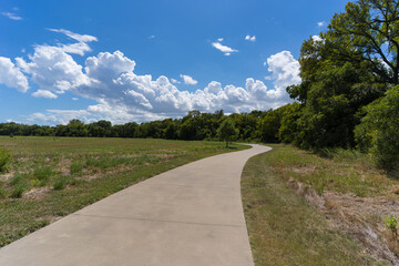 A concrete path in a Texas city park on a sunny August day.