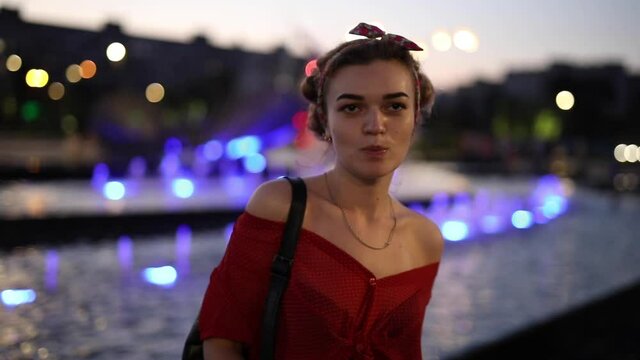 Funny woman blow the bubble with bubblegum near night fountain