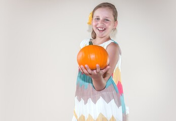 a girl with a smile holds a pumpkin in her hands
