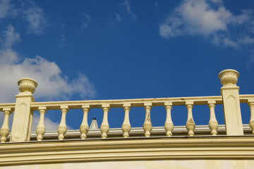 White decorative stone balustrade against the blue sky. Details of the baroque architecture of stone railings with white balustrades.