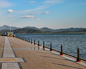 Obraz premium The evening sun sinks slowly in the west, casting shadows from the railings on to an ornamental walkway in a Turkish seaside resort.