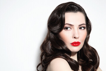 Fototapeta premium Young beautiful brunette with long curly hair and red lipstick
