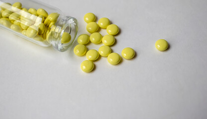 Yellow pills of valerian on a white background scattered near the jar