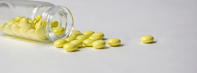 Yellow pills of valerian on a white background scattered near the jar