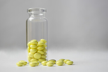 Yellow pills of valerian in a transparent jar on a white background