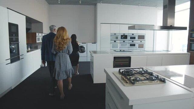 Senior couple buying new kitchen in store looking at furniture and appliance sample