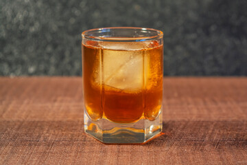 Glass of whiskey or cognac with ice on the table close-up, for design
