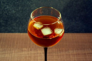 Glass of whiskey or cognac with ice on a wooden surface close-up, top view, for design