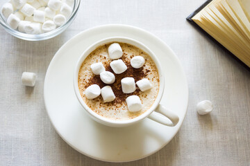 Still life with a Cup of coffee, marshmallows and a book. The concept of morning mood and comfort.