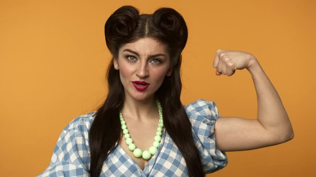 Smiling pin up woman pointing with finger at biceps