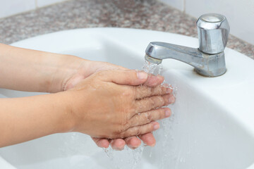 Hygiene concept cleaning hand and washing hands. A man washes his hands with soap and water in the basin.