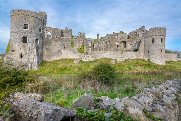 Fototapeta premium A view across a dry stone wall of the ruins of the old castle at Carew, Pembrokeshire, UK