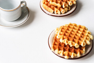 Round waffles for breakfast and coffee cup on white background.