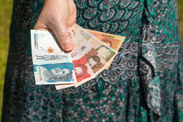 woman is holding Colombian pesos in her hand.
