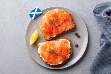 Sandwich, toast with smoked salmon and cream cheese on white plate, with Scottish flag. Grey...