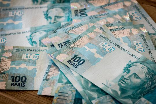 Many Brazilian banknotes 100 Reais scattered on the table.