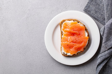 Sandwich, toast with smoked salmon and cream cheese on plate. Grey background. Copy space. Top view.