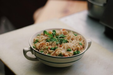 Bowl of noodles with vegetables isolated on wooden board with blurry background