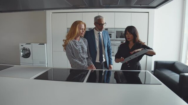 Senior couple picking stovetop for domestic kitchen in studio or furniture showroom