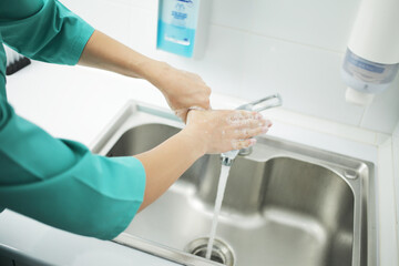 A woman doctor in protective mask washes hands thoroughly in hospital