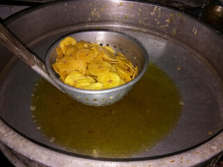 frying fresh sliced banana pieces in hot boiling oil in kitchen during  Onam celebration