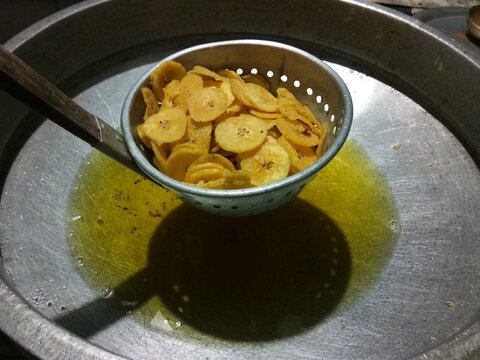 frying fresh sliced banana pieces in hot boiling oil in kitchen during  Onam celebration
