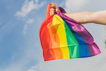 A male hand grasping the rainbow flag of the LGBT movement in a clenched fist. An expression of strength and determination in the fight for equality