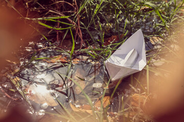 Origami paper boat sailing on the water. Autumn waters taking away all problems. Let your dreams set sail