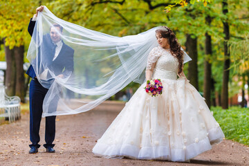 Fototapeta premium Newlyweds walk in the park and pose for a photographer